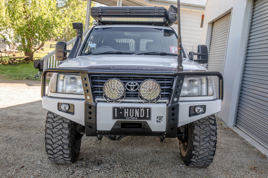 Toyota Land Cruiser with bull bar, spotlights, and roof-mounted light bar.