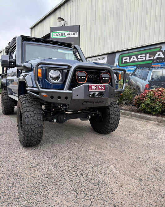 Off-road vehicle in front of Raslarr workshop with custom bumper and lights.