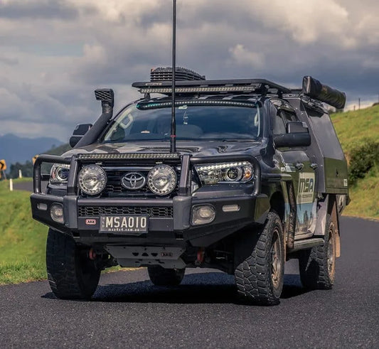 Off-road truck with custom bull bar and accessories driving on rural road.