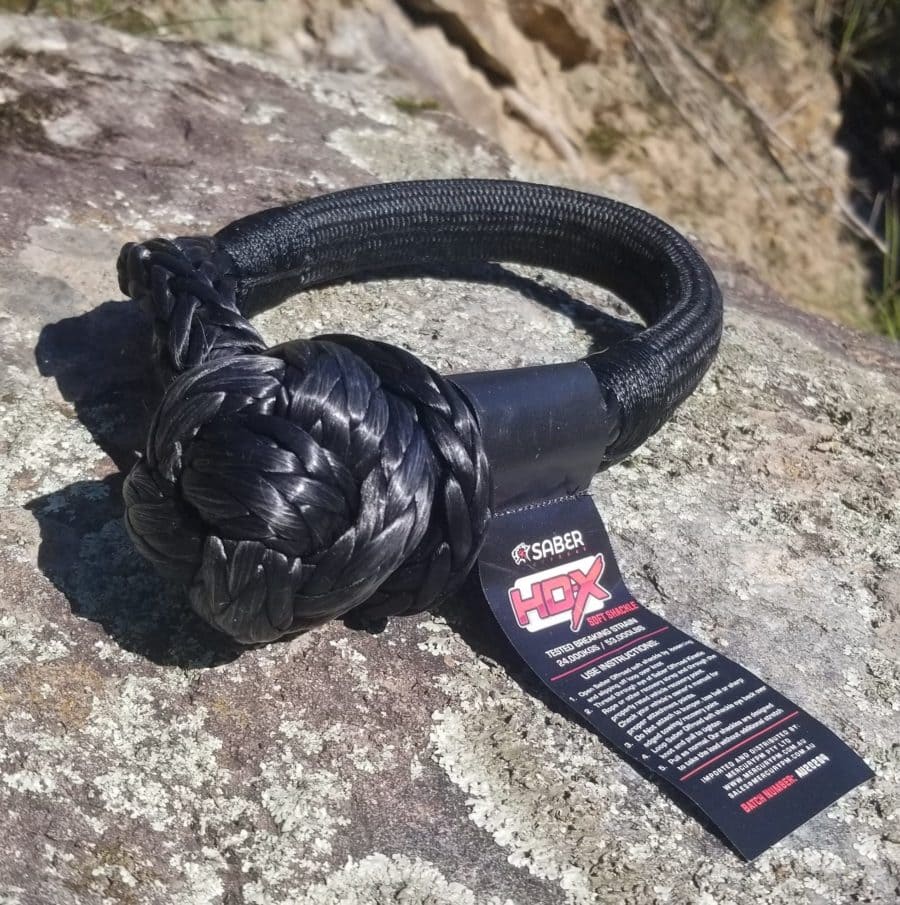 Black synthetic rope with Saber tag tied in a knot on rock surface.