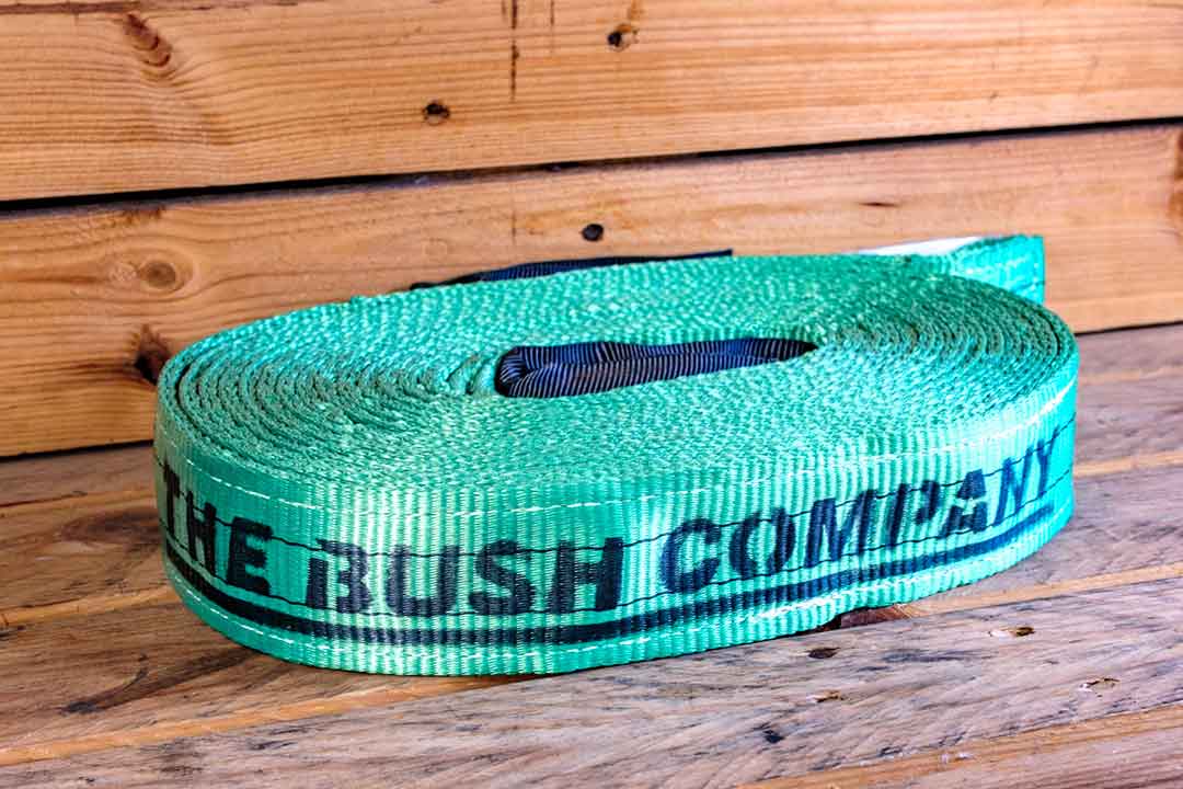 Green tow strap, "The Bush Company" printed, coiled on a wooden surface.