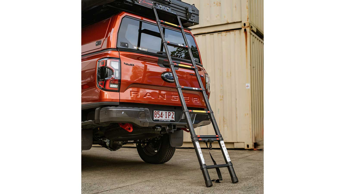 Foldable ladder leaning against orange Ford Ranger 4WD with roof rack.