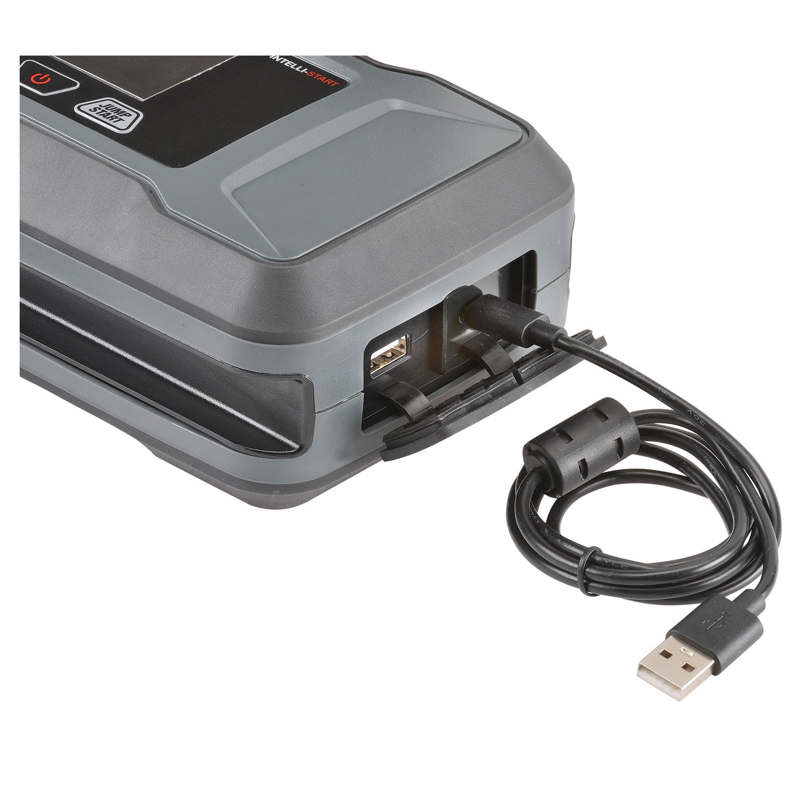 Close-up of a portable jump starter with a USB cable plugged into one of its ports, showing multiple output options including a standard USB and a 12V DC socket. The coiled USB cable is connected and ready for charging or power delivery.