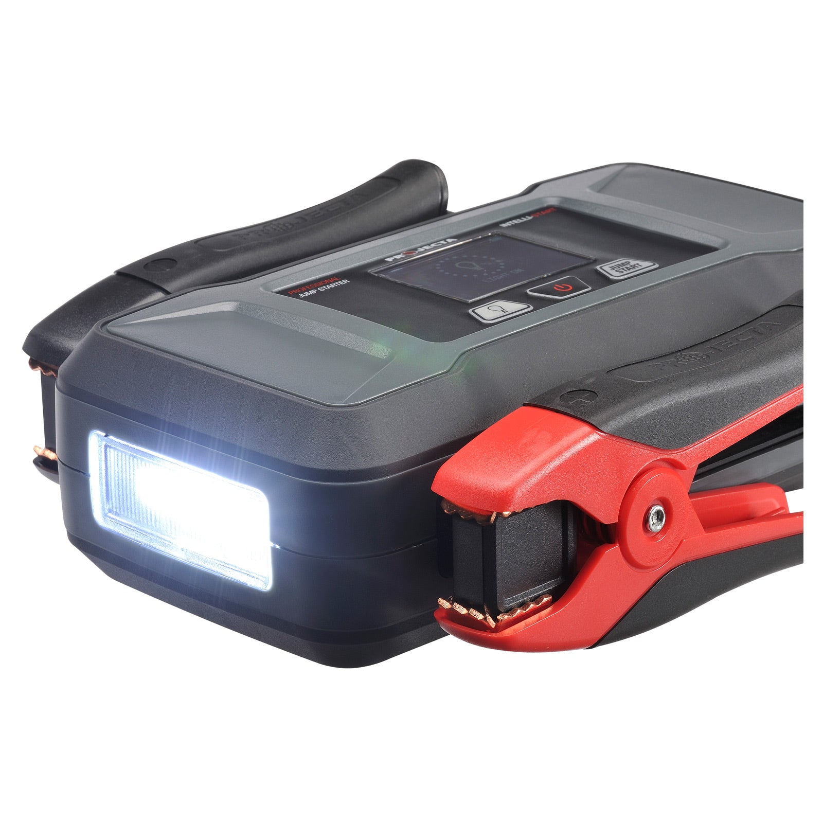 A close-up of a portable jump starter with its built-in LED torch switched on, next to a red and black jumper clamp with visible copper teeth. The screen interface and "Jump Start" button are also partially visible on the top panel.