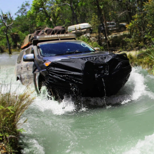 SUV with protective cover crossing a river, water splashing around.