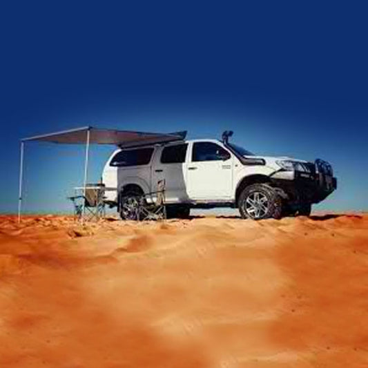 Off-road SUV parked in a desert with an awning and camping setup.