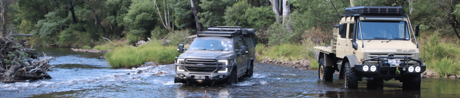 A picture of two 4WD vehicles crossing a brook.