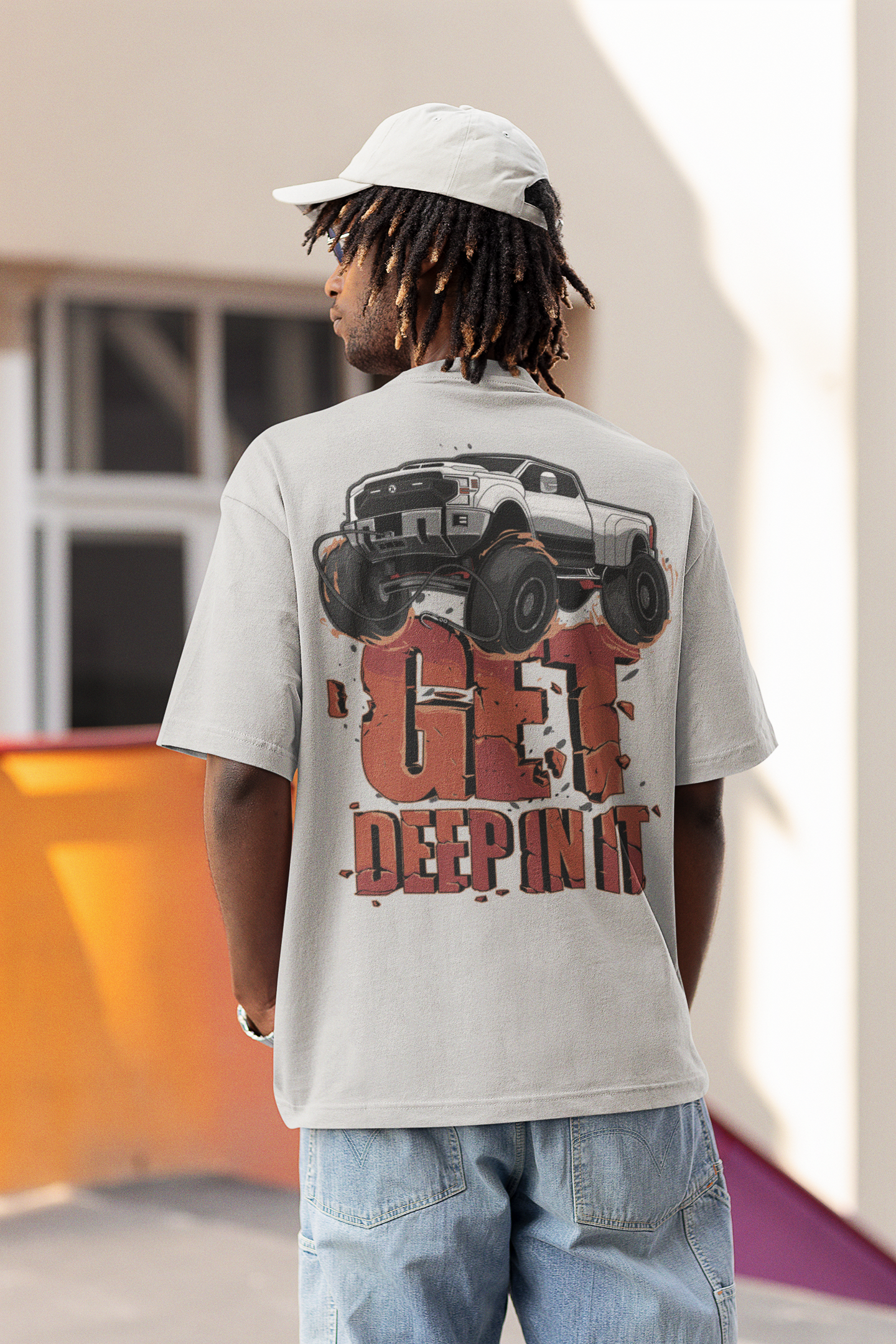 Back view of man in white cap and off-road-themed "Get Deep In It" t-shirt.