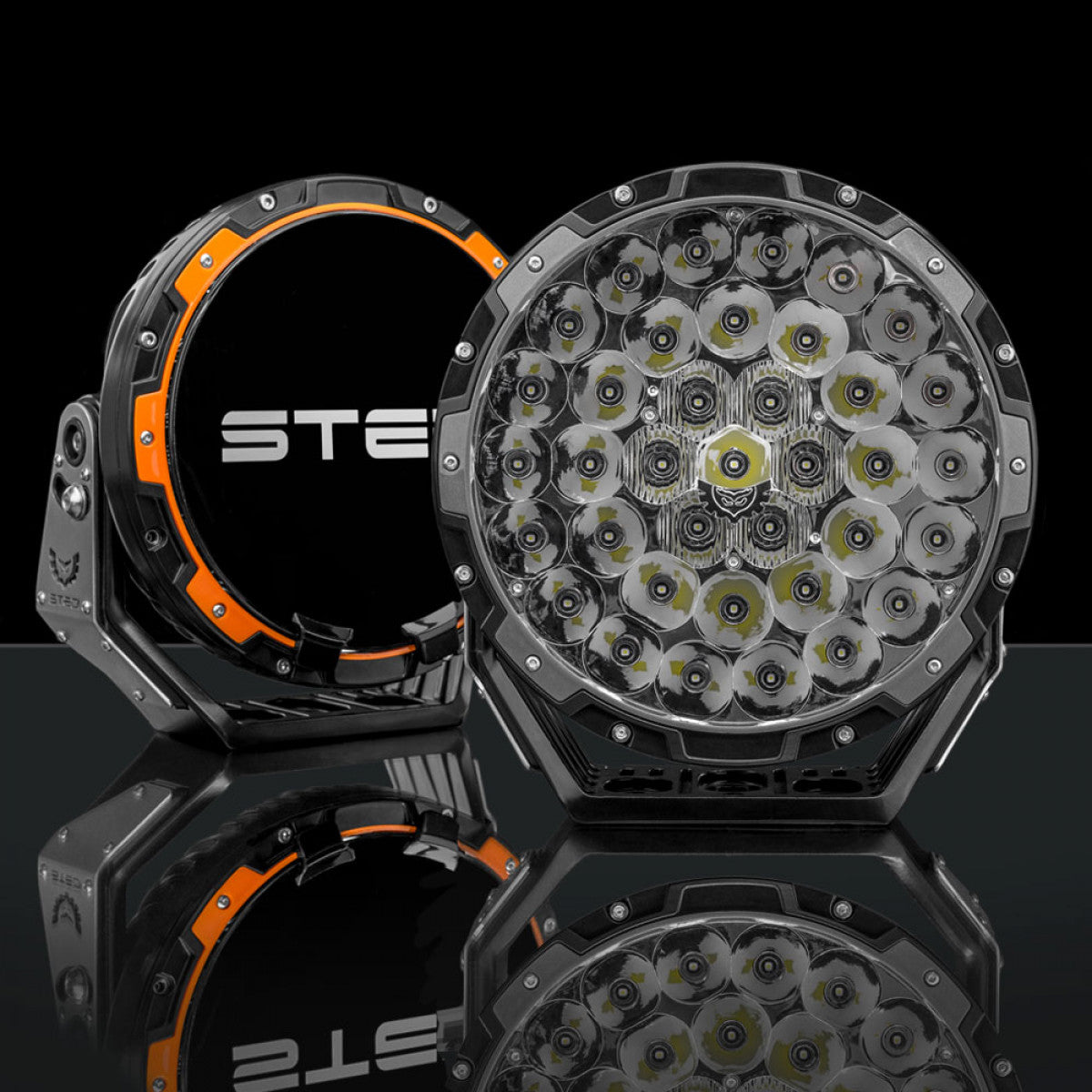 Pair of round LED lights, one facing forward, one with orange-black design, "STE".