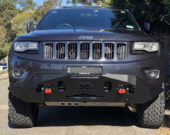 Front view of black Jeep with reinforced bumper, red tow hooks, outdoors.