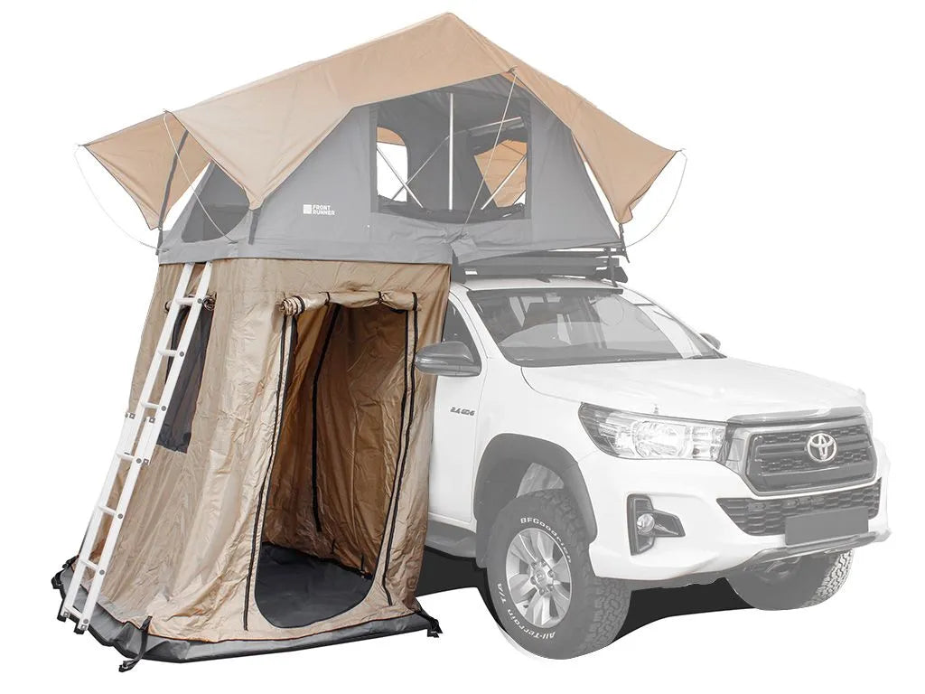 White truck with rooftop tent and annex, beige-gray tent, ladder for upper area.