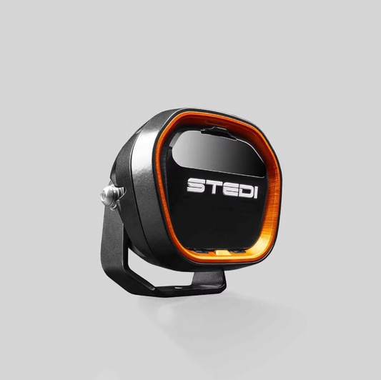 LED driving light with orange accent ring, STEDI brand, mounted on black bracket.